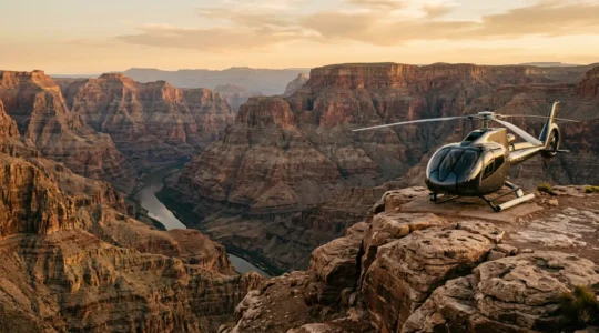 Helicopter soaring over the dramatic West Rim of the Grand Canyon with sunlit canyon walls and the Colorado River visible below