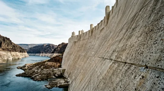 Dramatic upward view of Hoover Dam's curved concrete face towering over the Colorado River in Black Canyon