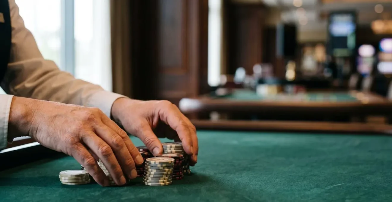 Medium shot of croupier hands arranging casino chips on roulette table felt in professional casino environment