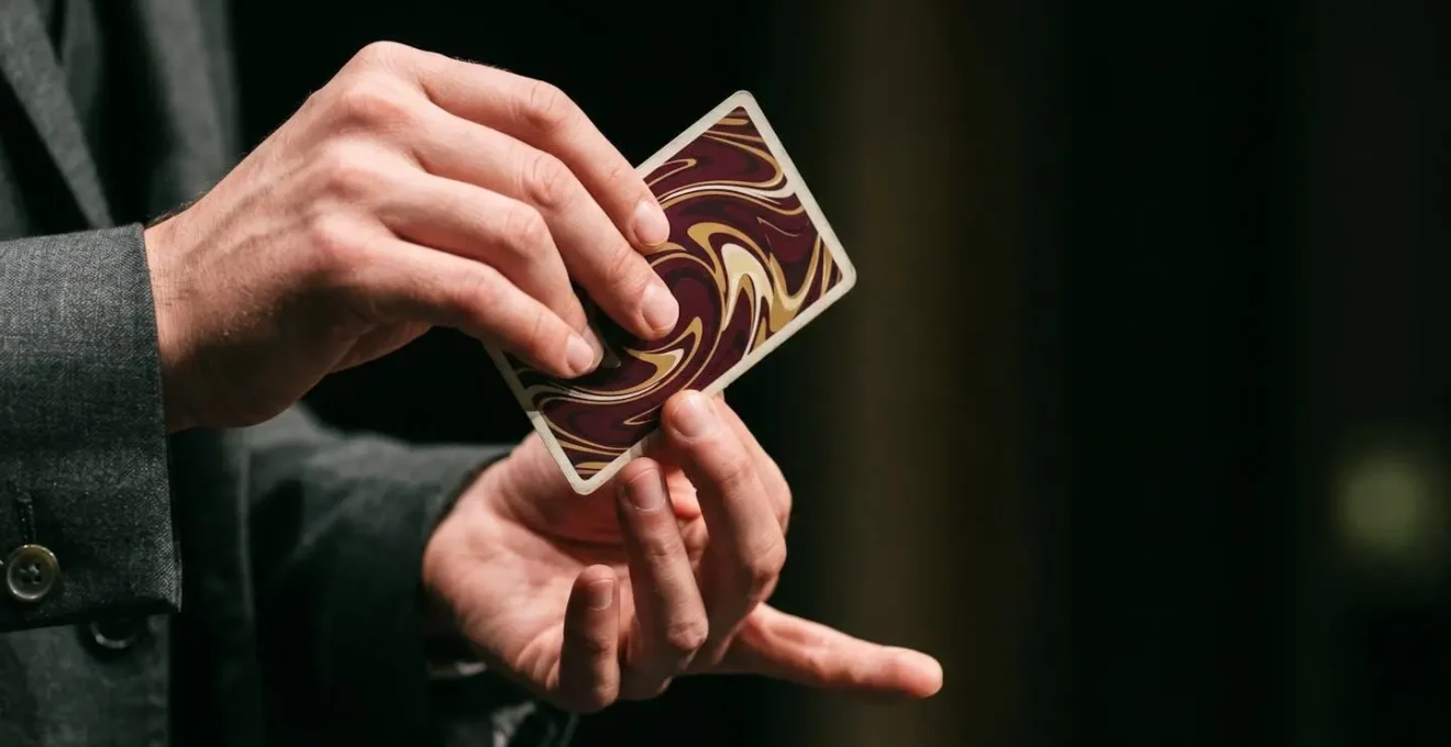 Extreme macro close-up of magician's hands mid-gesture with playing card creating sense of mystery and skill