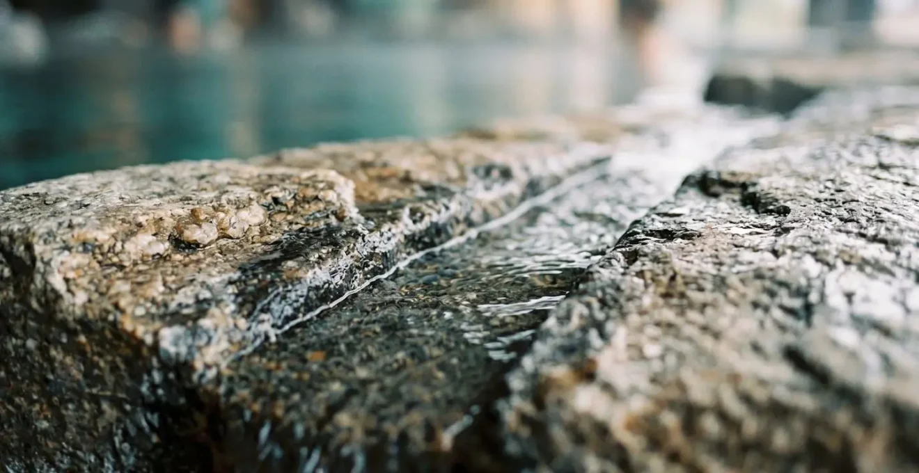 Close-up detail of luxury spa hydrotherapy circuit with natural stone textures and flowing water representing relaxation-focused resort amenities